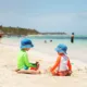 Two caucasian boys playing with sand at tropical beach