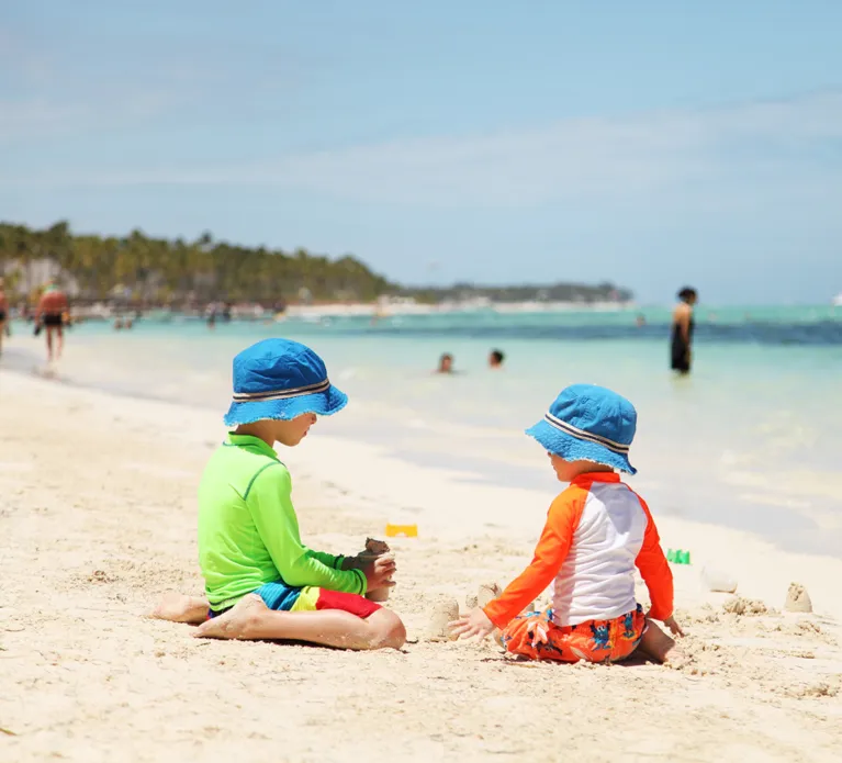 Two caucasian boys playing with sand at tropical beach