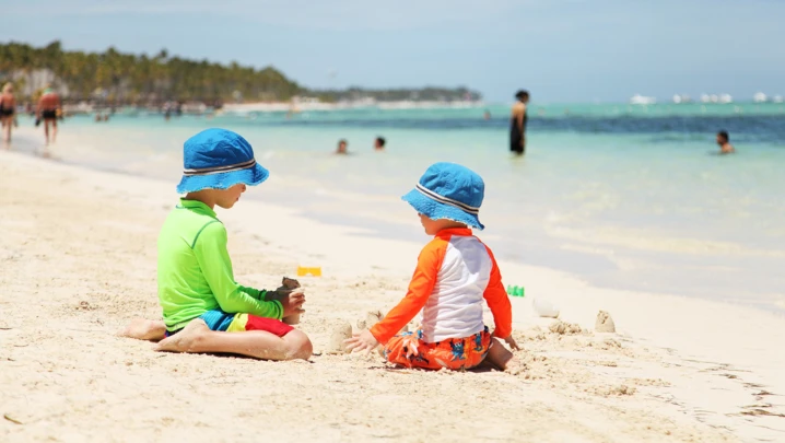 Two caucasian boys playing with sand at tropical beach