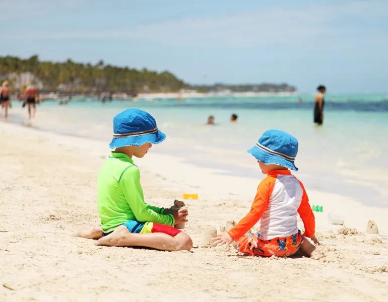 Two caucasian boys playing with sand at tropical beach