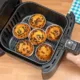 Top view of a hand baking homemade chocolate chips muffins in an air fryer.