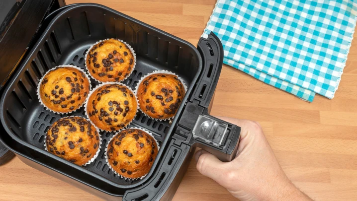 Top view of a hand baking homemade chocolate chips muffins in an air fryer.