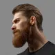 Young bearded man close-up portrait in profile. Excellent beard and hairstyle. Male model close up on a gray background.