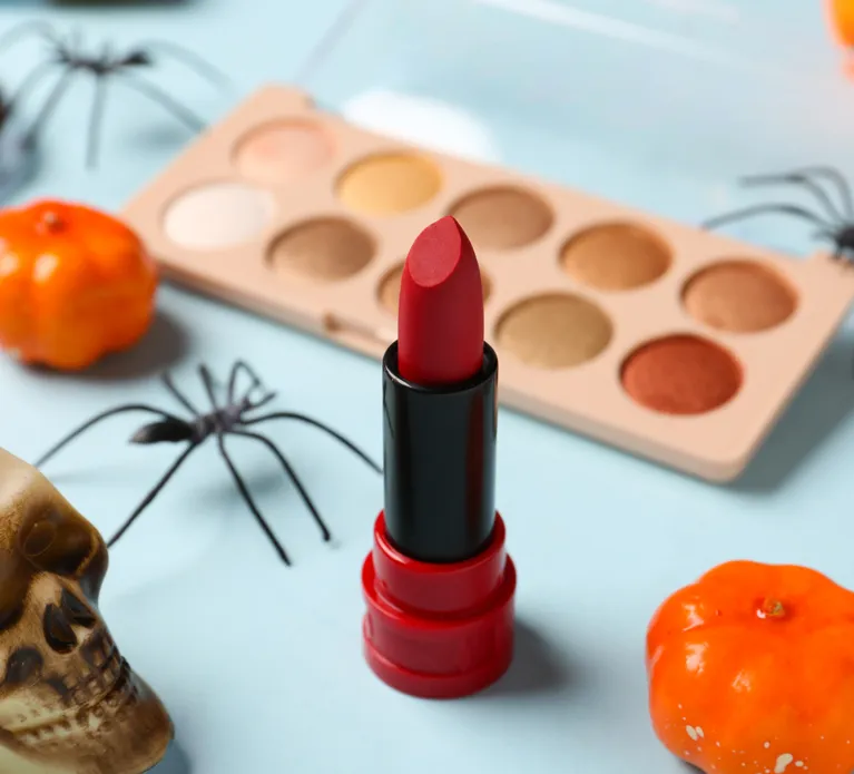 Different decorative cosmetics and Halloween decor on blue background