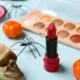 Different decorative cosmetics and Halloween decor on blue background