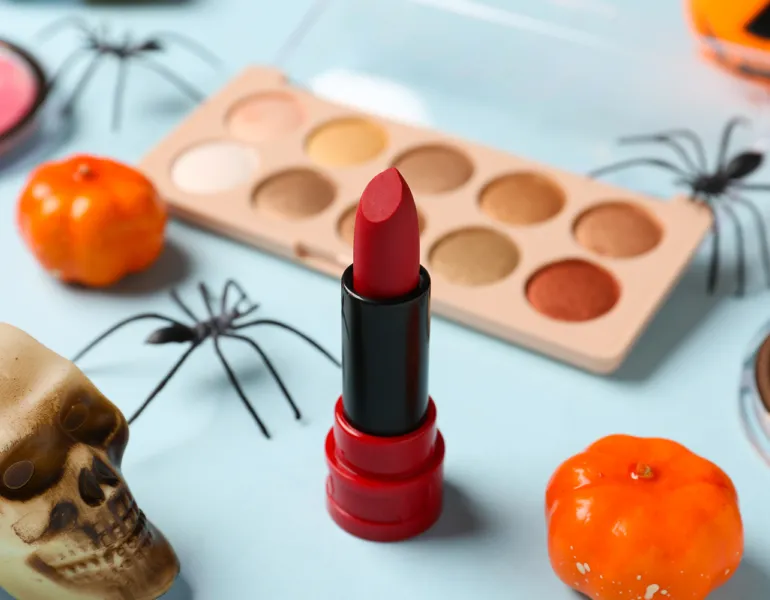Different decorative cosmetics and Halloween decor on blue background