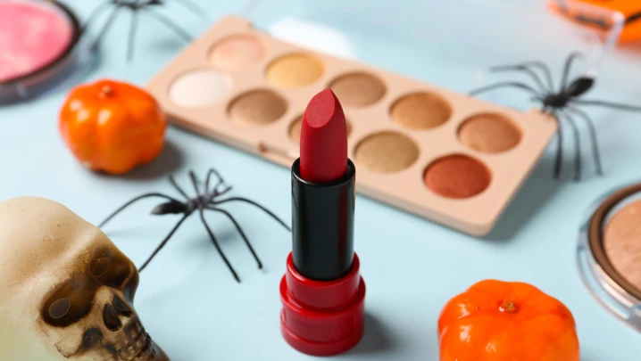 Different decorative cosmetics and Halloween decor on blue background